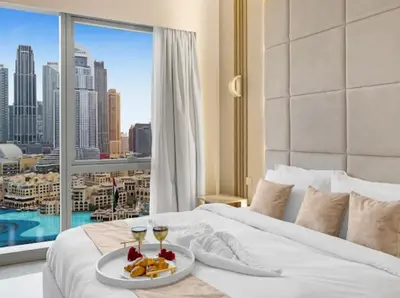 a bed with a plate of food and two glasses of wine at Ultra-luxury 2BHK apartment Stunning Burj Khalifa & Fountain view in Dubai