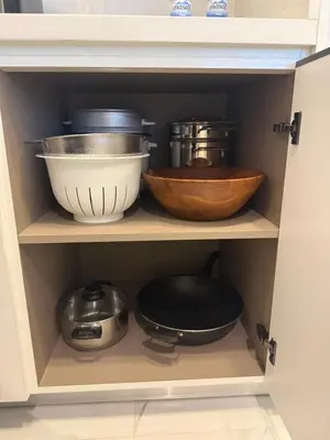 a cabinet filled with bowls and other kitchen utensils at Marina View 2BHK, Spacious Apartment in a Prime Location, Quick Access to Tram, Metro & Beach in Dubai