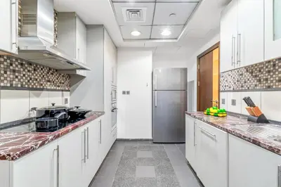 a kitchen with white cabinets and a stainless steel refrigerator at VayK - Spacious 3BR in JBR with Beach Access in Dubai