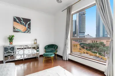 a living room with a green chair and a large window at VayK - Spacious 3BR in JBR with Beach Access in Dubai