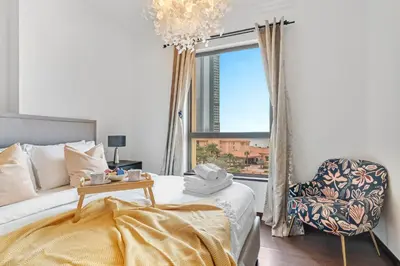 a bedroom with a bed and a chair and a window at VayK - Spacious 3BR in JBR with Beach Access in Dubai