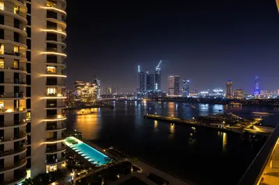 a city skyline at night with a river and buildings at Luxury Branded Suite with Direct Private Beach Access & Sea Views in Dubai
