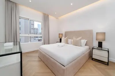 a white bedroom with a large bed and a window at Upgraded Serene 1BR Retreat in The Greens in Dubai