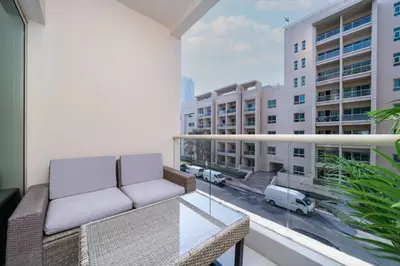a balcony with a couch and a view of a city at Upgraded Serene 1BR Retreat in The Greens in Dubai