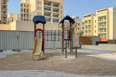 two playground equipment in a park with buildings at Upgraded Serene 1BR Retreat in The Greens in Dubai