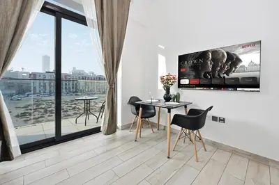 a living room with a table and chairs and a large window at Dubai JVC - Oxford Residence 2 - Parking&Balcony in Dubai