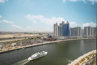 a boat traveling down a river in a city at Luxury Studio with Private Jacuzzi in Business Bay in Dubai