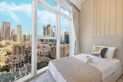 a bedroom with a large window with a city view at 3BR with Burj Khalifa View - Pool - Gym - Downtown in Dubai