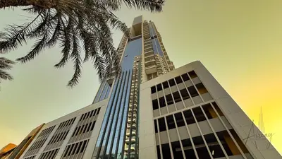 a tall building with a palm tree in front of it at Skyline View Stu 20th Floor Regina Tower, JVC in Dubai