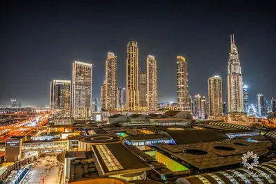 a city skyline at night with tall buildings at Emaar Residences Fashion Avenue - 1BR - Connected to Dubai Mall - Pool with Burj View in Dubai