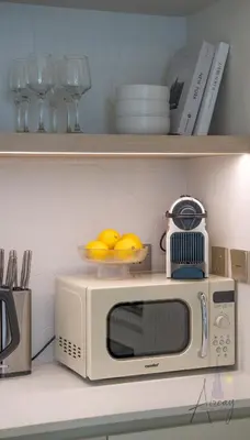 a microwave on a kitchen counter with plates and glasses at Elite Beachfront Living Stylish High-Floor 1BR in Dubai