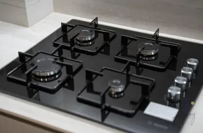 a stove top oven with black burners on it at Cosy Corner 1BR Designer Apt Luxe Nest in JVC in Dubai