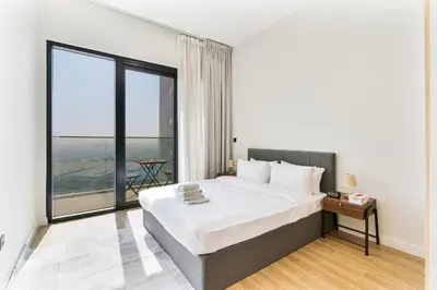 a bedroom with a large bed and a large window at Cozy 1BR Apartment, 20 Min to Jebel Ali Beach in Dubai
