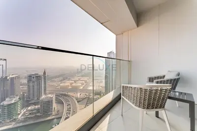 a chair on a balcony with a view of a city at Direct Beachfront Access, Connected to Address Beach Resort, Unmatched Walkability Near Cafes, Restaurants and Retail shops - Jumeirah Gate Tower, JBR by Deluxe Holiday Homes in Dubai