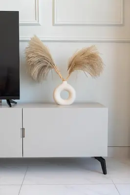 a vase with feathers on top of a white cabinet at Cozy 1BR at D1 Residence 13 with Stunning City View in Dubai