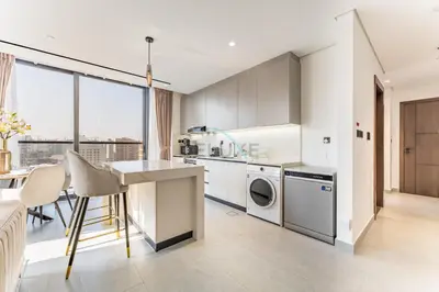 a kitchen with white cabinets and a table at Minutes from City Walk, Downtown Dubai and Jumeirah Beach, Easy Access to Metro Stations and Major Roads - Arista One, Al Satwa by Deluxe Holiday Homes in Dubai