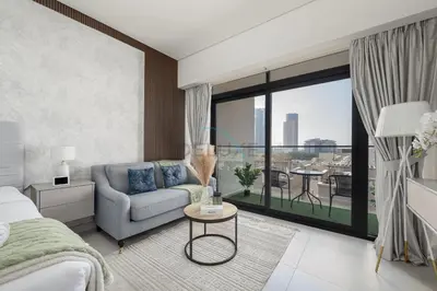 a bedroom with a bed and a couch and a large window at Prime Location, Near Bus Stop, Steps from the Park, Just 20 Minutes to Dubai Marina - Oxford Boulevard, Jumeirah Village Circle by Deluxe Holiday Homes in Dubai