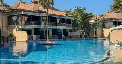 a swimming pool with a fountain in front of a building at 1BR Apartment Anantara Palm Private Beach in Dubai