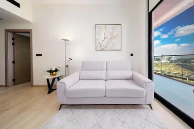 a white couch in a living room with a window at Stylish JVC Apt with Pool & Gym in Sabkhah