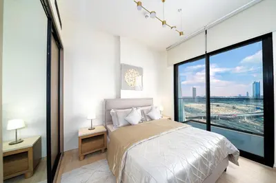 a bedroom with a bed and a large window at Stylish JVC Apt with Pool & Gym in Sabkhah