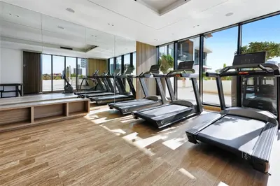a gym with a row of treadmills and mirrors at Stylish JVC Apt with Pool & Gym in Sabkhah