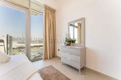 a bedroom with a large window and a dresser with a mirror at Full Burj Khalifa and Dubai Canal views, Minutes from Downtown and Dubai Mall - Farhad Azizi Residence, Al Jaddaf by Deluxe Holiday Homes in Dubai