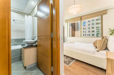a bedroom with a bed and a bathroom with a sink at 3BR with Sea View, Short Stroll From Marina Walk and JBR Beach, With Easy Access to Tram and Metro - Ocean Heights, Dubai Marina by Deluxe Holiday Homes in Dubai