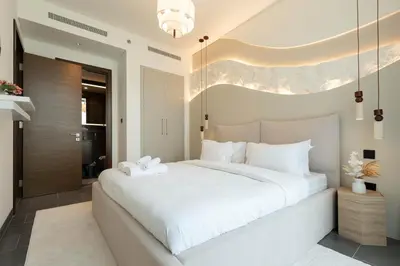 a bedroom with a large white bed with a chandelier at Luxury 1BR Apartment - Pool View - The Crest Dubai in Dubai