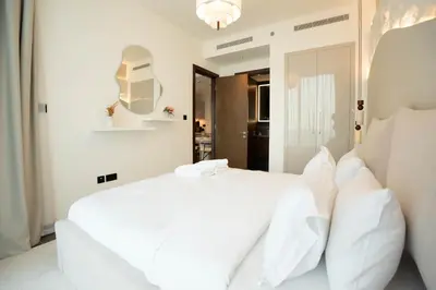 a white bedroom with a white bed with white pillows at Luxury 1BR Apartment - Pool View - The Crest Dubai in Dubai