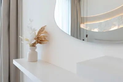 a white vase with flowers on a white shelf in front of a mirror at Luxury 1BR Apartment - Pool View - The Crest Dubai in Dubai