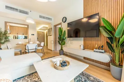 a living room with a couch and a tv on a wall at Walk from Burj Khalifa and Dubai Mall, and Conveniently Located near the Metro Station - BD Standpoint A, Downtown by Deluxe Holiday Homes in Dubai