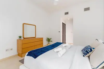 a white bedroom with a large white bed and a mirror at The Jewel Tower 2 in Dubai