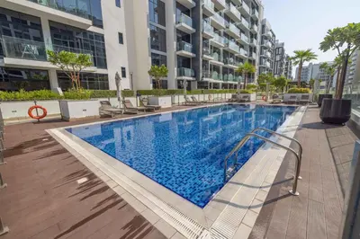 a large swimming pool with chairs and a building at Cozy Apartment in Azizi Riviera - 10 min to Burj Khalifa in Dubai