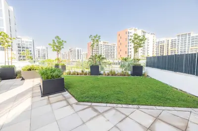 a garden with a lawn and buildings in the background at Cozy Apartment in Azizi Riviera - 10 min to Burj Khalifa in Dubai