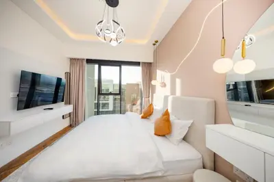 a bedroom with a white bed and a tv at Cozy Apartment in Azizi Riviera - 10 min to Burj Khalifa in Dubai