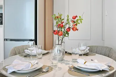 a table with plates and glasses and a vase with red flowers at Brand New 1BD in Address JBR, Relaxing Stay for 2 in Dubai