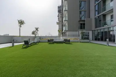 a lawn with chairs and tables in a building at Vogue Al Maktoum City Sobha Hartland Waves Near to Downtown, Burj Khalifa and Dubai Mall, One Bedroom Apartment plus Kids room with Balcony and City View, Access to all Amenities in Dubai