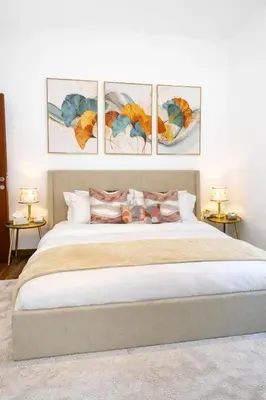 a bedroom with a large bed with four paintings on the wall at Lux 4BR JBR I Sea View I Walk to Beach I Sleeps 12 in Dubai