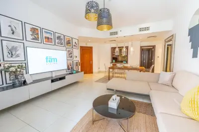a living room with a white couch and a tv at Fam Living Reehan Old Town 2BR Plus Maids Apt in Dubai