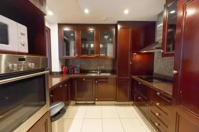 a kitchen with wooden cabinets and a sink at Fam Living Reehan Old Town 2BR Plus Maids Apt in Dubai