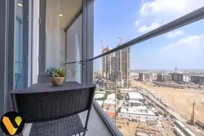a balcony with a chair and a view of a city at Vogue Al Maktoum City Sobha Hartland Waves Near to Downtown, Burj Khalifa and Dubai Mall, One Bedroom Apartment plus Kids room with Balcony and City View, Access to all Amenities in Dubai