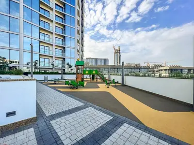 a building with a playground in front of a building at Vogue Al Maktoum City Sobha Hartland Waves Near to Downtown, Burj Khalifa and Dubai Mall, One Bedroom Apartment plus Kids room with Balcony and City View, Access to all Amenities in Dubai