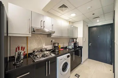 a kitchen with white cabinets and a washer and dryer at Chic Studio Canal Side Speedy wi-fi BBay in Dubai