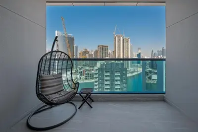 a rattan chair in a room with a large window at Chic Studio Canal Side Speedy wi-fi BBay in Dubai