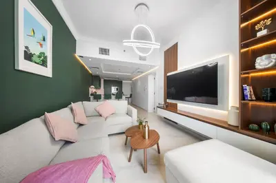 a living room with a white couch and a tv at Emerald Luxury Suite DMCC Metro station in Dubai