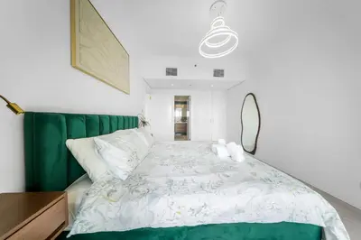 a bedroom with a large bed with a green headboard at Emerald Luxury Suite DMCC Metro station in Dubai