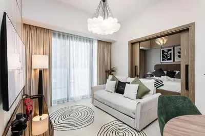a living room with a couch and a bedroom at Stylish 1BR Apartment at Damac Hills Golf Gate in Dubai