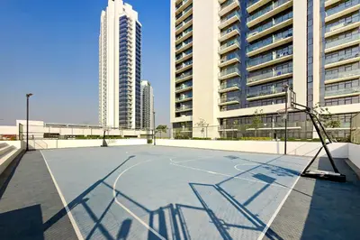an empty basketball court in a city with tall buildings at Stylish 1BR Apartment at Damac Hills Golf Gate in Dubai