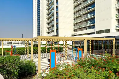 a playground in front of a tall building at Stylish 1BR Apartment at Damac Hills Golf Gate in Dubai