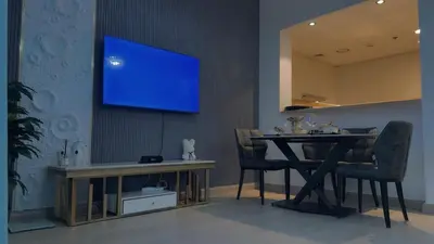 a dining room with a table and a tv on the wall at Central Downtown 1BR - Walk to Dubai Mall in Dubai